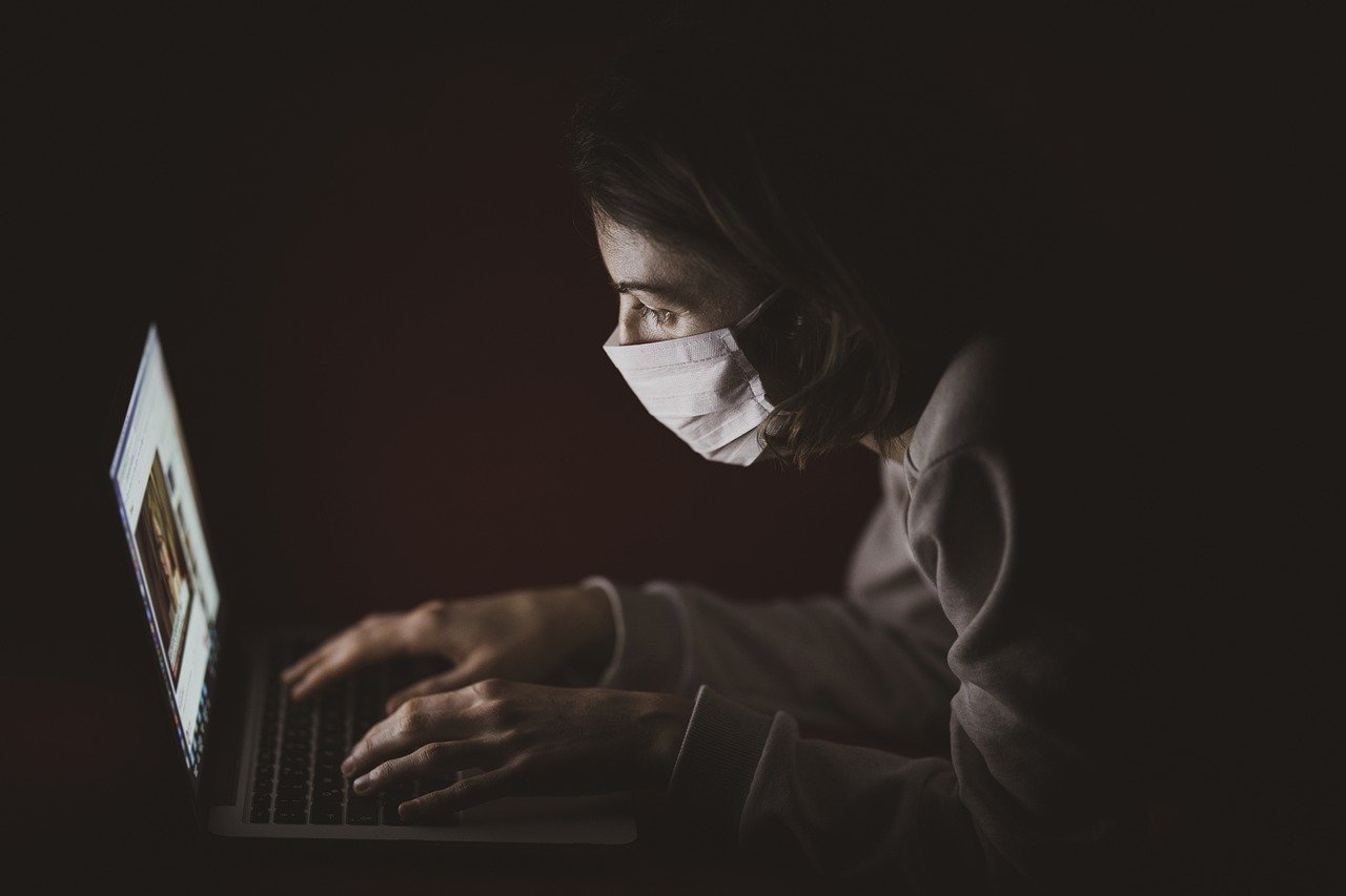 Chica trabajando en su ordenador con mascarilla